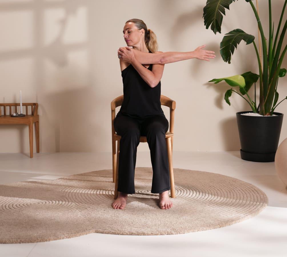 A woman stretching through a seated chair yoga pose